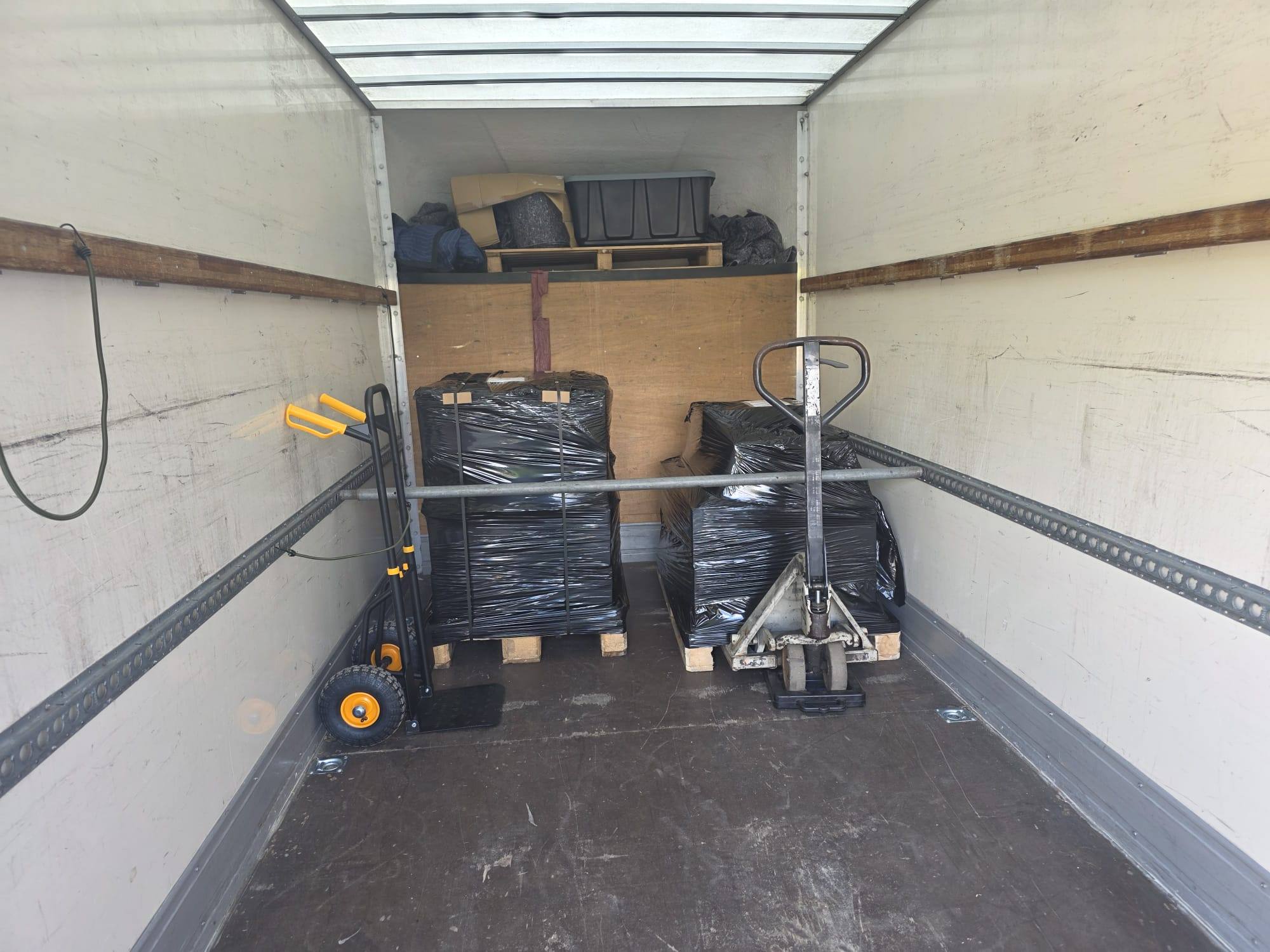 Two wrapped pallets loaded in the Luton van, with the pallet truck on board